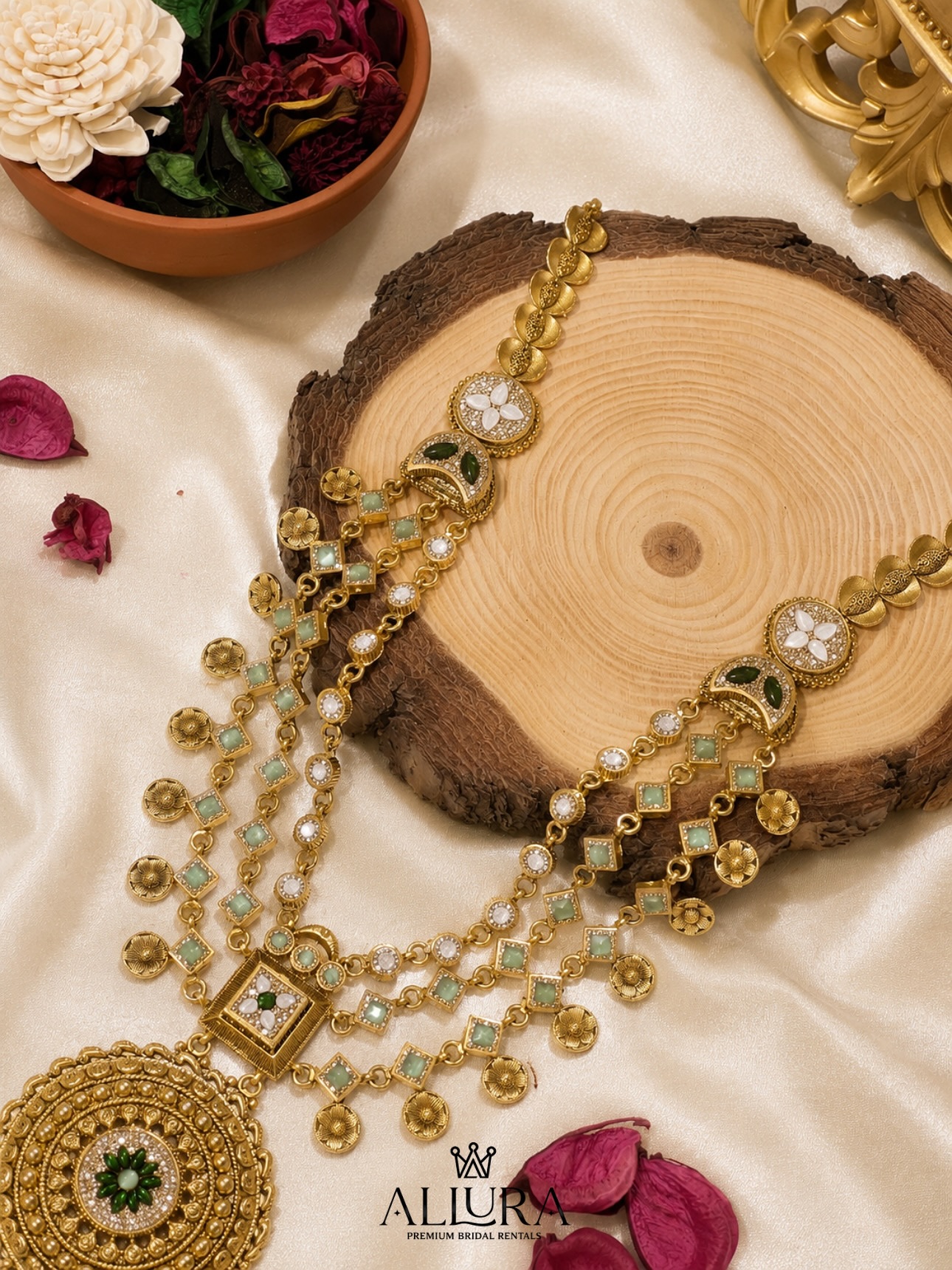 Antique-gold bridal necklace, jhumkas and matha-patti laid on marble with rose petals